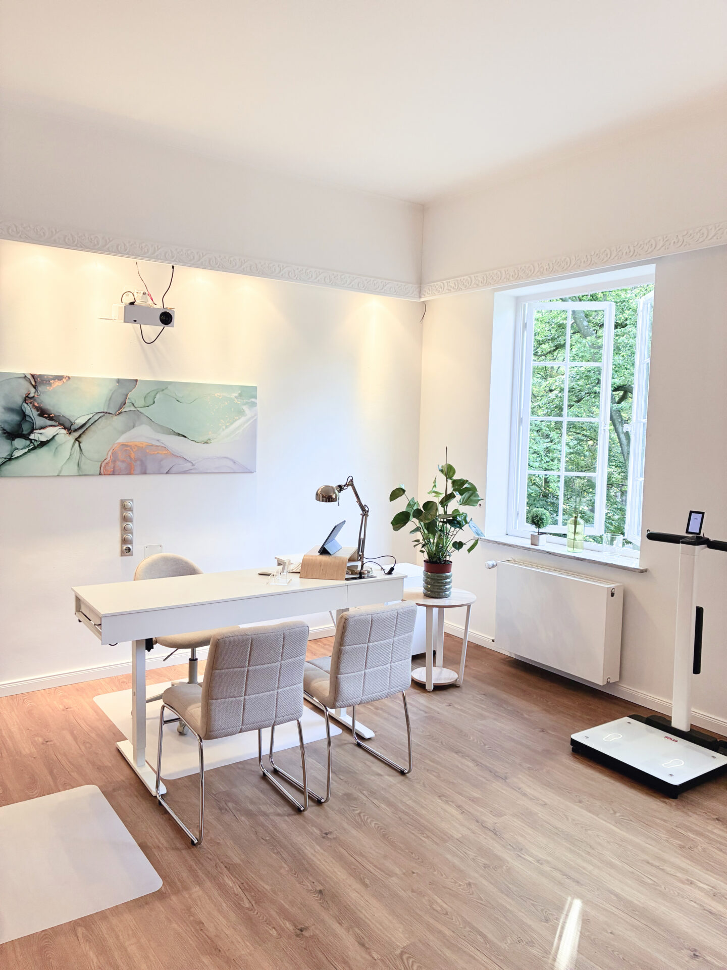 Modernes Büro mit hellem Interieur, einem eleganten Schreibtisch, zwei Stühlen und einer Zimmerpflanze. 